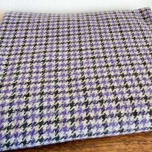 May include: A white ceramic mug with a black handle and the text "But First, Coffee" in a bold, black font. The mug is set against a blurred background, suggesting a cozy setting.