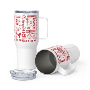 May include: White travel mugs with red graphics and text. One mug is upright, the other is on its side. The text includes "Twenty One Pilots", "Breach", and "Downstairs". The mugs have handles and clear lids.