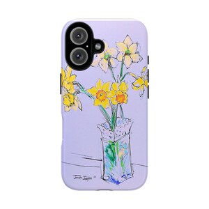 Puede incluir: Una funda de teléfono morada con una ilustración de acuarela de un ramo de narcisos amarillos en un jarrón de vidrio transparente con un borde de encaje blanco. La firma del artista es visible en la esquina inferior derecha.