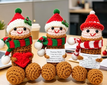 May include: Three crocheted figures with tan cylindrical bodies, wearing red and white hats with green accents. Each has a smiling face and a scarf. One holds a red heart, while the other two hold white cards with printed text messages.