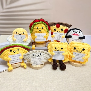 May include: A set of eight crocheted food-themed plushies, each holding a sign with a positive message. The plushies are made in various colors, including yellow, brown, white, and red. The plushies are all smiling and have cute faces. The signs include messages such as "Teacher, you're spec-tace-lar!" and "It's okay to fall apart sometimes."