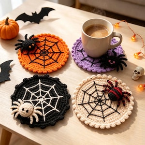 May include: Four round crochet coasters featuring spider web patterns in orange, purple, black, and beige. Each coaster includes a small, attached plush spider. The orange coaster has a black spider, the purple has a black spider, the black has a white spider, and the beige has a red and black striped spider.