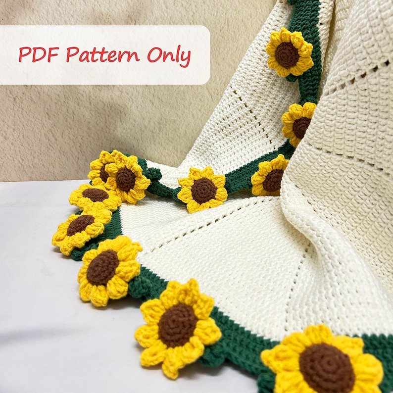 K&ouml;nnte beinhalten: Eine wei&szlig;e H&auml;keldecke mit gr&uuml;nem Rand und geh&auml;kelten Sonnenblumen-Applikationen. Die Decke ist in der H&auml;lfte gefaltet und die Sonnenblumen sind am Rand der Decke sichtbar. Der Text "PDF Pattern Only" ist in der oberen linken Ecke des Bildes sichtbar.