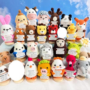 May include: A selection of vibrant, handmade crochet animal figures, such as a rabbit, cow, sheep, and fox. Each figure holds a small sign with positive affirmations. The figures are displayed on wooden stands.
