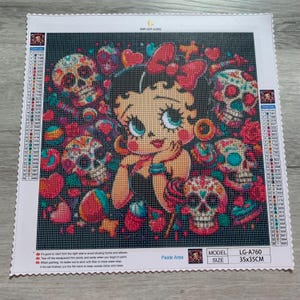 May include: A diamond painting kit featuring a Betty Boop design with sugar skulls, hearts, and a lollipop. The artwork is set against a dark background. The kit size is 35x35cm.