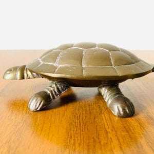 Joyero vintage de latón con forma de tortuga, con tapa abatible. Sirve para guardar joyas, alfileres y otros objetos pequeños.