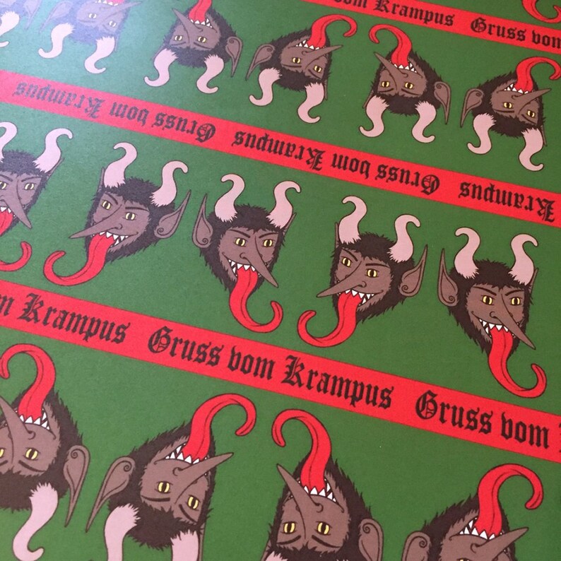 May include: A green and red wrapping paper with a repeating pattern of red-tongued, horned, black and white creatures. The paper has the text "Krampus Gruss vom Krampus Gruss vom" repeated across the paper.
