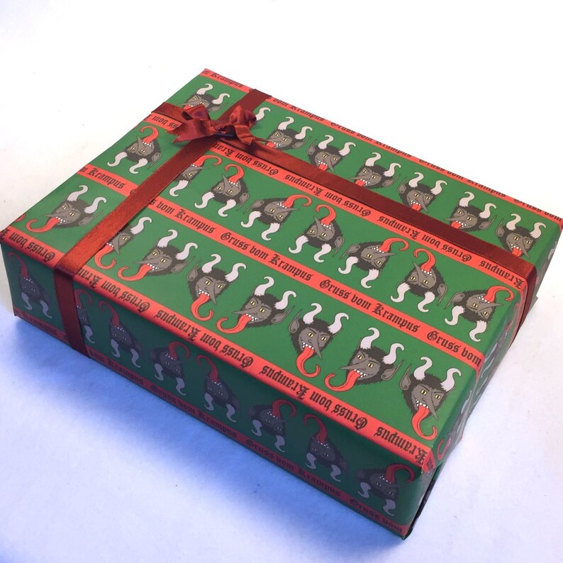 May include: Green gift wrap with a repeating pattern of red-tongued, horned creatures with the text "Gruss vom Krampus" in red gothic lettering. The gift is tied with a red ribbon.