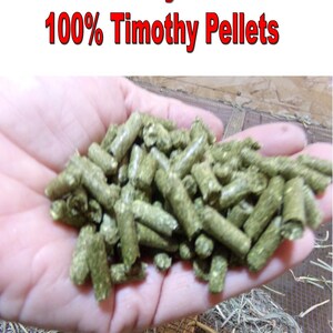 May include: A handful of green Timothy hay pellets. The image includes the text "Dakota Hay Products" and "100% Timothy Pellets" in red. The pellets are cylindrical and appear to be a feed product.