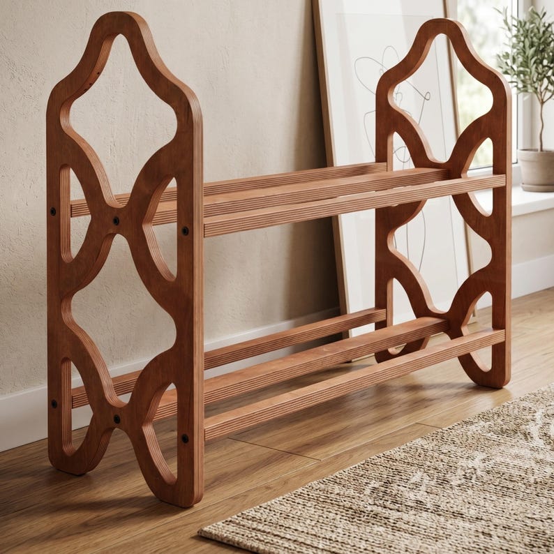 May include: A wooden shoe rack with a decorative, openwork design. The rack has three shelves and is made of light brown wood. The sides feature an intricate, geometric pattern. The shoe rack is placed on a wooden floor.