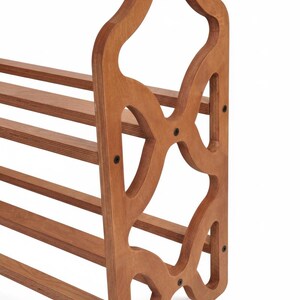 May include: Wooden shoe rack with a decorative cutout design on the side panel. The rack has multiple horizontal shelves for shoe storage. The wood has a warm, natural finish, and the design is functional and stylish.