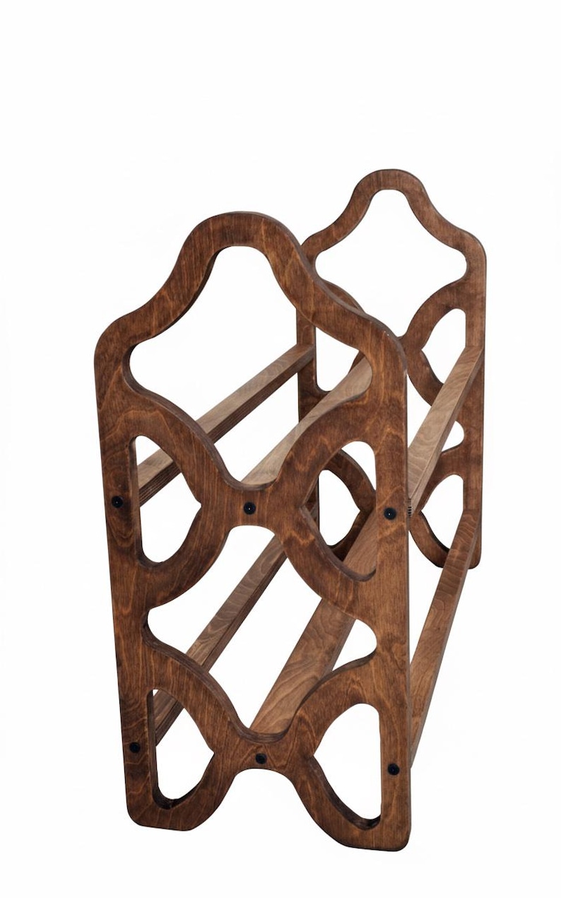 May include: A wooden wine rack with a dark brown finish. The rack has a decorative, openwork design with curved edges and holds multiple bottles. The construction features horizontal supports and is held together with black hardware.