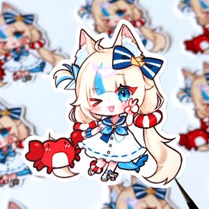 Puede incluir: Una pegatina con un personaje de dibujos animados con orejas de gato, ojos azules y pelo rubio con mechones azules. El personaje lleva un vestido blanco con detalles azules y sostiene un cangrejo rojo. La pegatina tiene un borde blanco.
