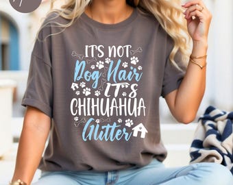 May include: A gray t-shirt with the text "It's not Dog Hair It's Chihuahua Glitter" in white and blue lettering. The text is surrounded by paw prints and bone designs.
