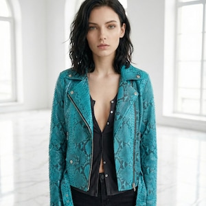 May include: A turquoise snakeskin-patterned jacket with a silver zipper and buckle details. The jacket has a classic biker style with a notched collar and a fitted silhouette. The model is wearing a black shirt and black pants.