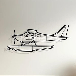 May include: A black metal wall sculpture of a seaplane with floats. The sculpture is mounted on a white wall above a white couch with beige pillows.