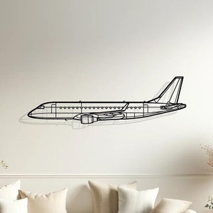 Può includere: Un contorno di aereo in metallo nero montato su una parete bianca sopra un divano bianco con cuscini beige. L'aereo è in vista di profilo.