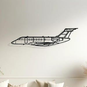 Può includere: Arte da parete in metallo nero che rappresenta un jet privato in volo. L'opera d'arte è esposta su una parete bianca sopra un divano bianco con cuscini beige.