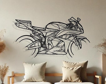 May include: A black line art illustration of a motorcycle on a white wall. The motorcycle is in a side profile view. The motorcycle is hanging on the wall above a light wood couch with two white pillows. There are two dried flower arrangements in vases on either side of the couch.