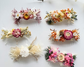 May include: Six floral hair combs with dried flowers in various colors, including pink, orange, white, and yellow. The combs are arranged on a white surface, showcasing the intricate details of each floral arrangement. Perfect for weddings or special occasions.