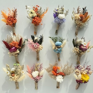Könnte beinhalten: Eine Sammlung kleiner Trockenblumensträuße in verschiedenen Farben, darunter Orange, Lila, Weiß und Gelb. Jeder Strauß ist mit Bindfaden gebunden. Die Blumen sind in verschiedenen Formen und Größen angeordnet und erzeugen eine rustikale und natürliche Ästhetik.