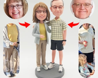 Puede incluir: Una figura personalizada de una pareja de pie juntos. La figura está hecha de cerámica pintada y presenta detalles realistas. La pareja lleva ropa informal y sonríe.