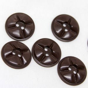 May include: Six brown plastic buttons with four raised lines and two holes in the center.