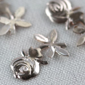 May include: Silver metal rose charms with a detailed design. The charms are perfect for jewelry making, scrapbooking, and other craft projects.