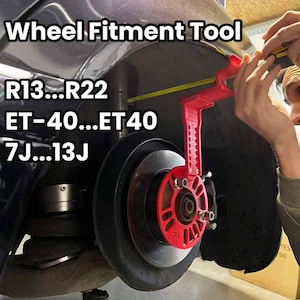 Puede incluir: Una herramienta roja de ajuste de ruedas se utiliza en el conjunto de la rueda de un coche. La herramienta mide el ajuste de la rueda, con texto que indica la compatibilidad para ruedas R13 a R22, ET-40 a ET40 y 7J a 13J. La herramienta es roja.