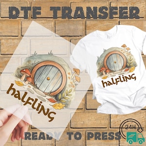 May include: A white t-shirt with a "halfling" graphic, featuring a round wooden door, mushrooms, and autumn leaves. A DTF transfer with the same design is shown next to the shirt. The words "READY TO PRESS" are at the bottom.