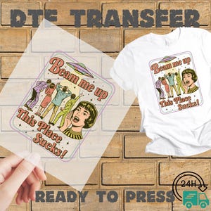 May include: White t-shirt with a retro graphic that says "Beam me up, This Place Sucks!" featuring a vintage illustration of people looking up at a UFO. A ready-to-press transfer of the same design is also shown.
