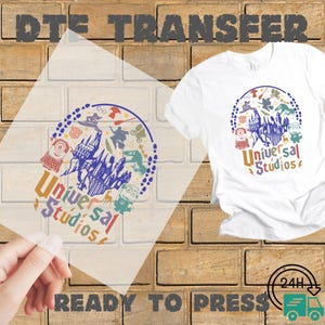 May include: White t-shirt with a colorful Universal Studios graphic. The design includes the text "Universal Studios" and various cartoon characters and icons. A clear DTE transfer is shown next to the shirt, with the words "READY TO PRESS" at the bottom.