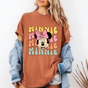 Może przedstawiać: Biały ceramiczny kubek z czarnym uchwytem i napisem "But First, Coffee" pogrubioną, czarną czcionką. Kubek jest umieszczony na neutralnym tle, podkreślając jego prosty design. Kubek ma około 10 cm wysokości.