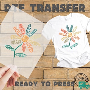 May include: White t-shirt with a floral design composed of positive words like "brave," "kind," and "strong." The words are in various colors. The words "Ready to Press" are at the bottom.