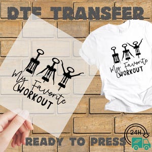 May include: A white t-shirt with the text "My Favorite Workout" and a graphic of three corkscrews. A clear ready-to-press transfer with the same design is held in front of a brick wall.