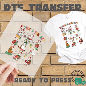 May include: White t-shirt with a colorful graphic of cartoon geese dressed in Santa hats and holiday attire, with the words "Physical Therapy" in a curved design. A clear transfer sheet with the same design is held in front of the shirt.