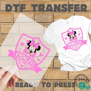 May include: A white t-shirt with a pink graphic of Minnie Mouse wearing glasses and a bow, inside a shield with the words "Princess Security". A DTF transfer of the same design is shown next to the shirt. The words "Ready to Press" are at the bottom.