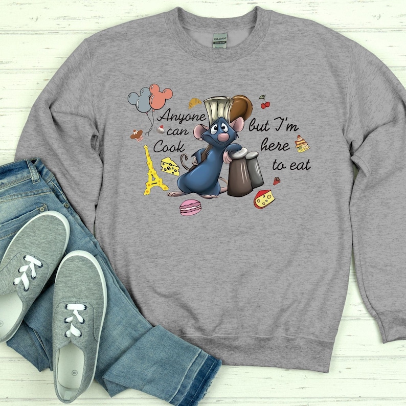 May include: A gray sweatshirt featuring a cartoon rat chef with the text "Anyone can cook but I'm here to eat." The design includes illustrations of the Eiffel Tower, cheese, and a macaron.