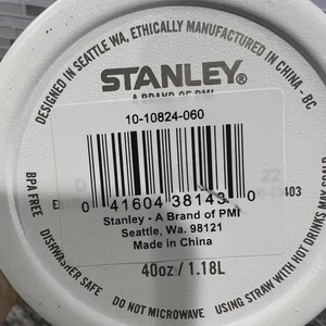 K&ouml;nnte beinhalten: Wei&szlig;e Wasserflasche der Marke Stanley mit Etikett. Das Etikett enth&auml;lt den Text "Designed in Seattle WA, Ethically Manufactured in China - BC", das Stanley-Logo und einen Barcode. Die Flasche ist 1,18 l und BPA-frei.