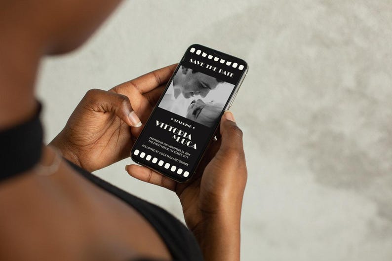 May include: A black and white photo of a couple on a smartphone screen with a save the date announcement for a wedding. The text reads "Save the Date" and "Vittocia & Luca" with the date "November 18, 2024" and the location "The Event Venue, 123 Street City".
