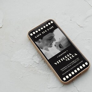 May include: A black and white photo of a couple on a smartphone screen with a film strip border. The text reads "Save the Date" and "Starring Vittoria & Luca" with the date and location of the event.