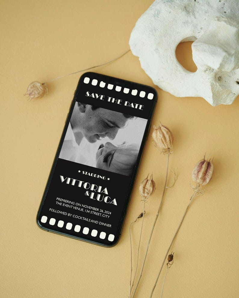 May include: A black and white photo of a couple on a smartphone screen with a black background and white text that says "Save the Date", "Starring", "Vittoria & Luca", "Premiering on November 26, 2024", "The Event Venue, 134 Street, City", and "Followed by Cocktails and Dinner".