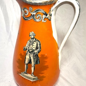 Puede incluir: Jarra de cerámica naranja con asa blanca y borde decorativo. La jarra presenta una ilustración en blanco y negro de un hombre con abrigo y calzones. La jarra es de estilo vintage.