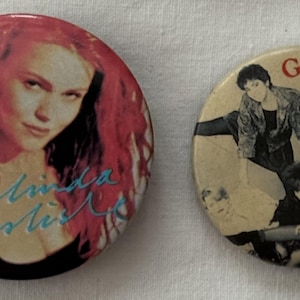 May include: Two round button pins. One features a portrait of Belinda Carlisle with the text "Belinda Carlisle" in blue and white. The other features a group of people with the text "GO-GO's" in red and white.