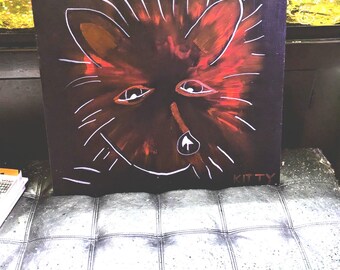 May include: A red and white abstract painting of a fox's face on a black background. The painting is signed "KITTY" in the bottom right corner.