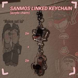 Puede incluir: Un llavero enlazado con dos dijes de acrílico. Los dijes tienen un diámetro de 5 cm y presentan personajes de dibujos animados. El texto "SANMOS LINKED KEYCHAIN (acrylic charm)" y "*Makes out lol*" es visible en la imagen.