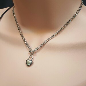May include: A silver chain necklace with a heart-shaped padlock pendant.