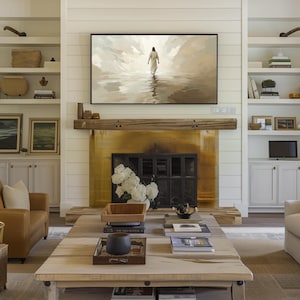 a cozy living room with a fireplace, a large painting of a person walking, and a wooden coffee table with various items on it.