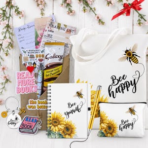 May include: A gift set featuring a white canvas tote bag, a spiral-bound notebook, and a zippered pouch, all decorated with sunflowers and bees. The set includes a gold pen, a metal keychain, a book-shaped charm, and paper inserts labelled Book Review and Reading List, plus a packet of Galaxy hot chocolate.