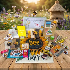 May include: A mystery box set featuring a Bee VIP Mystery Book Box, a yellow Never Give Up notebook, a sunflower-themed cloth with the text bee happy, an Aero chocolate bar, a Galaxy chocolate bar, bee-themed stickers, cards, and stationery.